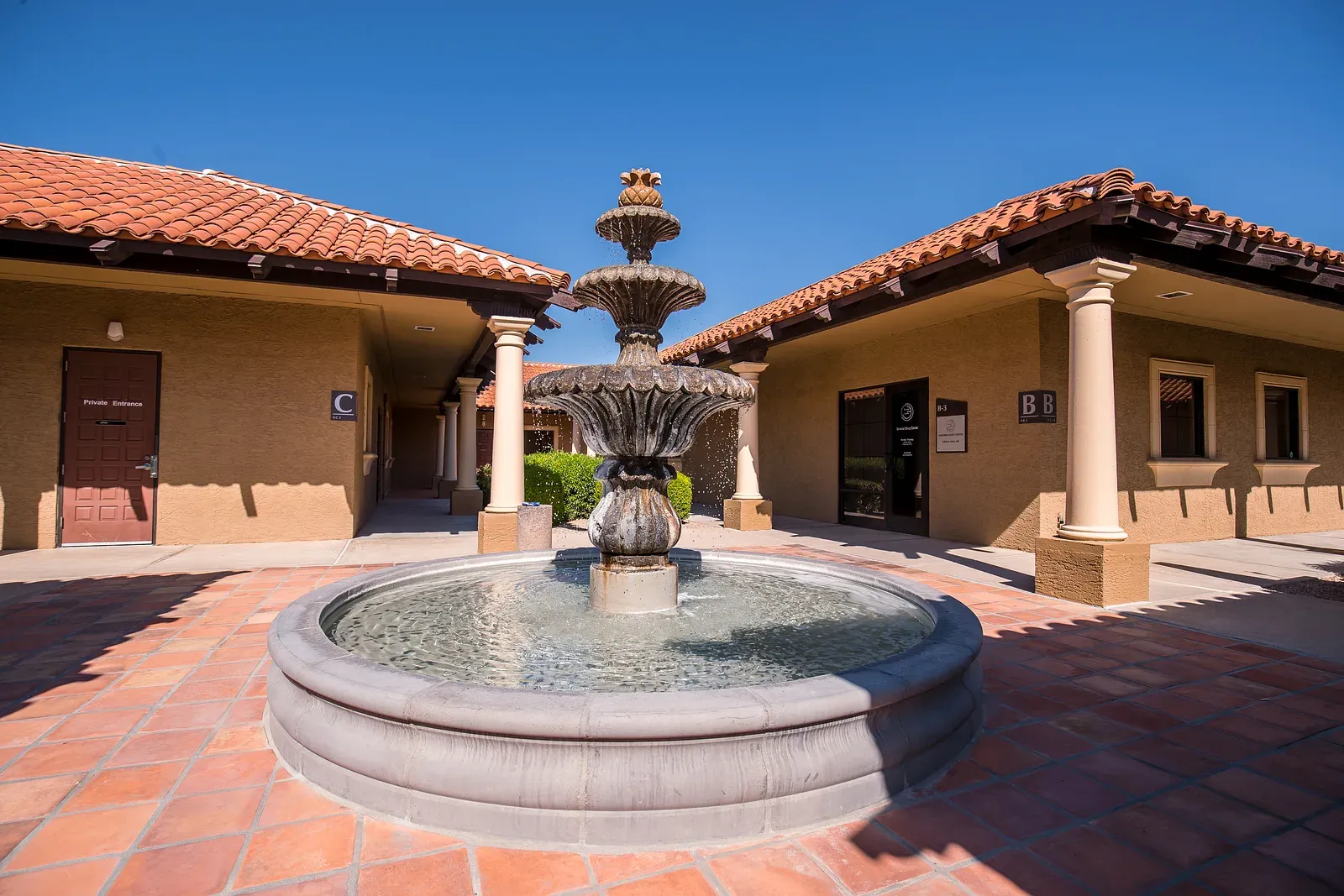 The fountain courtyard at Sonoran Sleep Center's Glendale, Arizona clinic, framed by mission-style colonnades under a clear desert sky